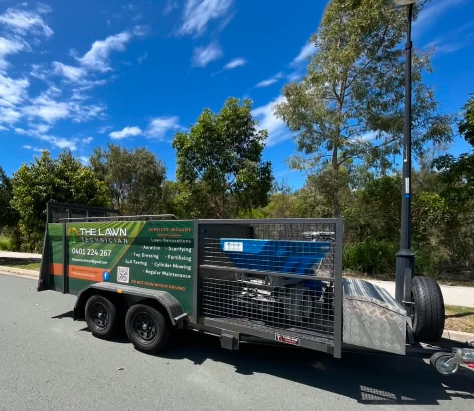 The Lawn Technician equipment trailer parked beside professional lawn care machinery